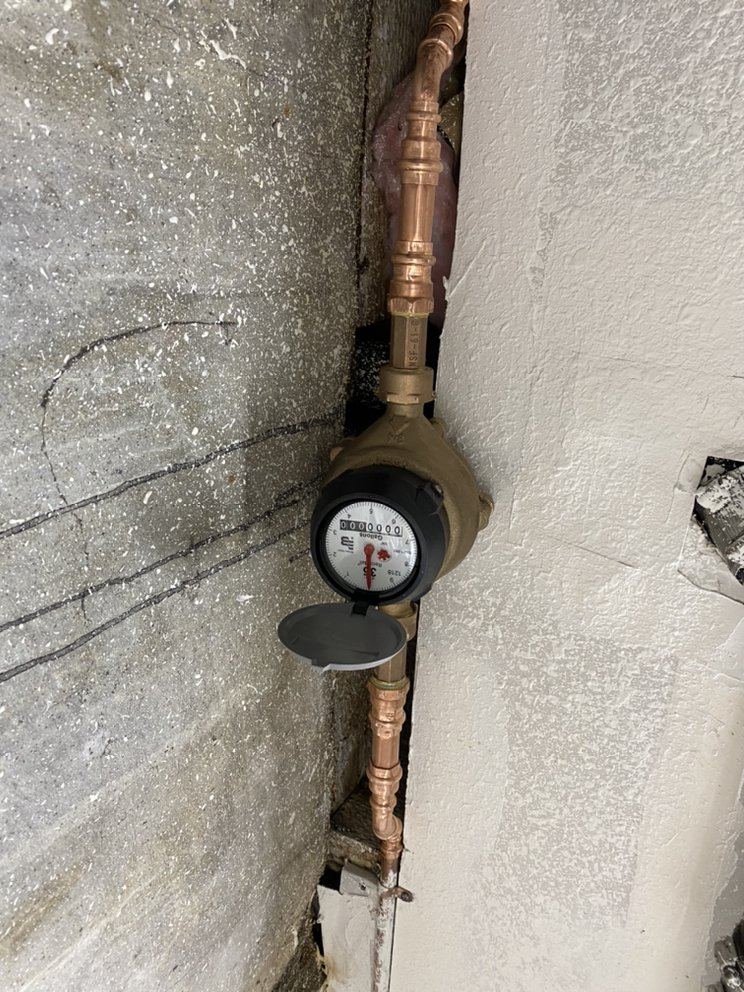 Water meter and shutoff valve on exterior wall connection